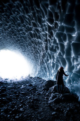 junge Frau fasst eiskalte Wand einer Eishöhle an