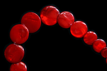 Red necklace from round flat beads on a dark background close up