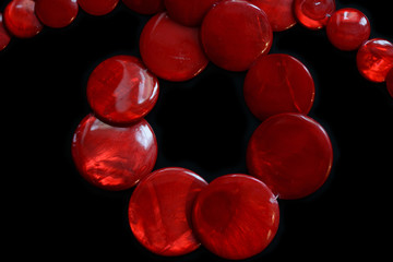 Red necklace from round flat beads on a dark background close up