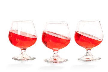 Three brandy glasses with red drink tilted inside