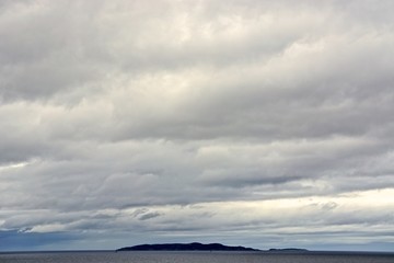 An island off the west coast of Scotland, with a thick layer of clouds overhead.