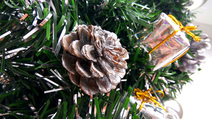 Close up view artificial Christmas tree brunches decorated with silver bauble, toy present boxes and cone. New Year holiday decorations photography