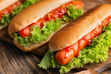 Tasty hot dogs with salad on wooden table, closeup