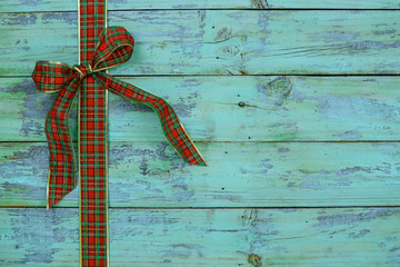 Blank rustic antique teal blue wood sign with red and green plaid Christmas bow border; holiday background with aged painted copy space