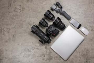 Photography equipment to travel on bare mortar background, DSLR camera,  Lenses, laptop, mouse and...