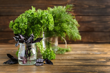 Jars with fresh aromatic herbs on wooden table