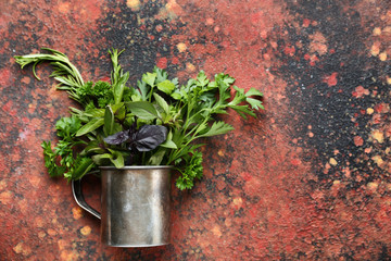Metal cup with fresh aromatic herbs on color background