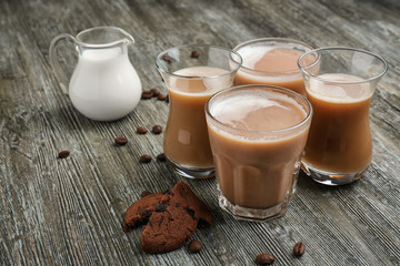 Glasses with tasty aromatic coffee and jug of milk on wooden table