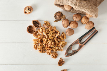 Nutcracker and sack with walnuts on white table