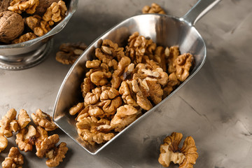 Scoop with tasty walnuts on grey table