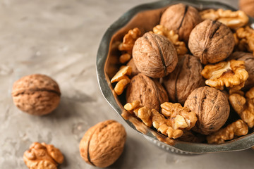 Bowl with tasty walnuts on grey table