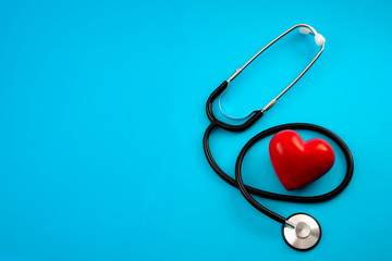 Yearly health check up, disease diagnosis medicine, healthcare and cardiology concept with a red heart and a stethoscope isolated on a hospital blue background with copy space - obrazy, fototapety, plakaty
