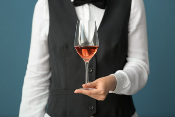 Waiter with glass of wine on color background, closeup