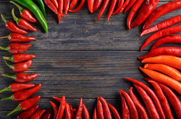 Frame made of fresh chili peppers on wooden background