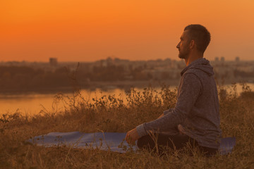 Man doing yoga on sunset with city view,Padmasana/Lotus position .