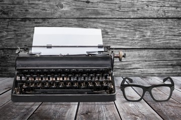 Retro black typewriter and spectacles on wooden