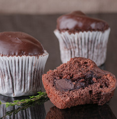 Mafine with chocolate and chocolate glaze. Served with coffee beans and thyme. On a black tile