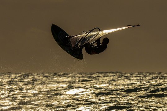 Backlit windsurfer jumping, Southern France, France, Europe