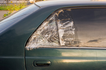 broken dark car rear window sealed with scotch tape