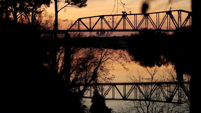 People walking on old train bridge at sunset