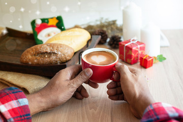 Male hands holding a cup of coffee drink near bread on tray, heart pattern in a coffee cup, top view