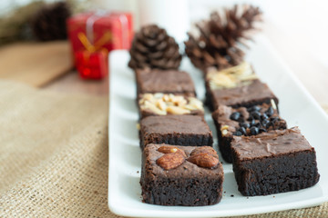 Brownie chocolate cake on white plate, with Christmas decoration background,.selective focus