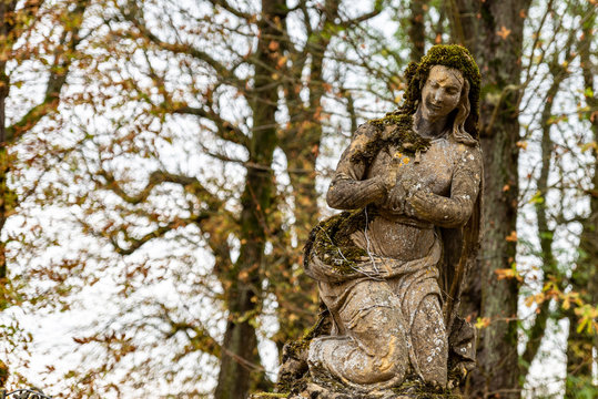 Statue religieuse sans mains couverte de mousse d'un cimetière en Moselle