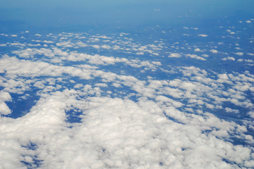 The sky and clouds and the view seen in the window of the plane.