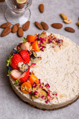 White cake with berries on the table with nuts, cinnamon, a glass, lemon.