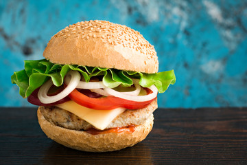 Tasty fresh closeup burger and french fries on wooden table. Homemade hamburger with fresh vegetables.