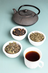 Cup of tea and teapot with three different tea