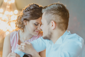 beautiful young couple hugging, lovers on lights background and garlands, holiday, family, Christmas