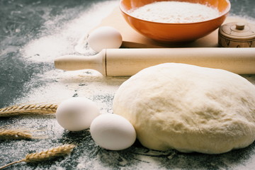 Dark Baking background with white eggs and flour.Dark blue background with a wooden spoon flour,eggs, flour and rolling pin. The process of baking, cooking.Top view, space for text.