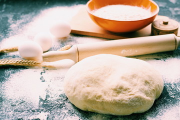 Dark Baking background with white eggs and flour.Dark blue background with a wooden spoon flour,eggs, flour and rolling pin. The process of baking, cooking.Top view, space for text.