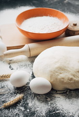 Dark Baking background with white eggs and flour.Dark blue background with a wooden spoon flour,eggs, flour and rolling pin. The process of baking, cooking.Top view, space for text.