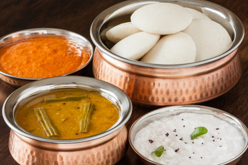 Indian idly with chutney and sambar - Fresh steamed Indian Idly (Idli / rice cake) arranged in authentic copper bowl. Served with tomato chutney, coconut chutney and sambar. Natural light used.