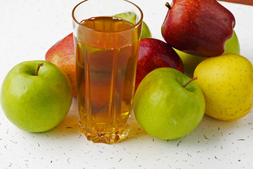  Apple juice in a glass and apples on the table.