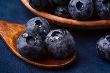 bog whortleberry in a wooden spoon on a blue background