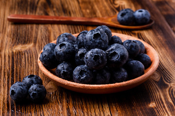 bog whortleberry in a clay cup with a wooden spoon on a wooden table