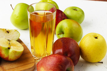  Apple juice in a glass and apples on the table.