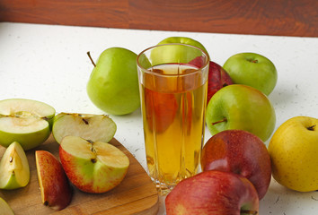 Apple juice in a glass and apples on the table.