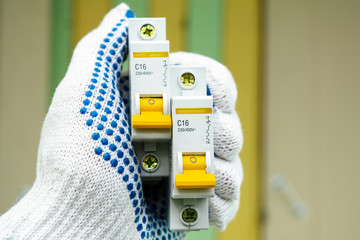 circuit breakers in hand against a colored wall background