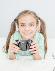 Happy little girl playing video games at home