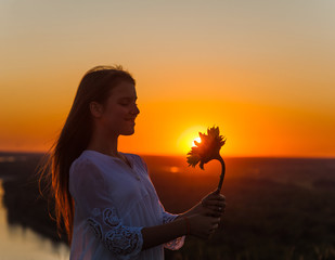 Happy girl with a magic flower at sunset. Empty space for text