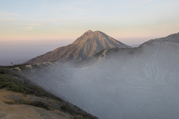 Sunrise hues with a smoke filled crater at Mount Ijen in East Java, Indonesia