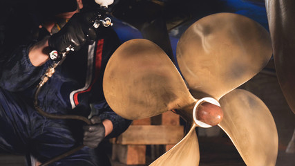 The yacht technician cleans the propeller using a chemical spray (paint) cleaner from dirt. Concept from: New technique, Chemistry, Profesional, Paint, Respirator, Mask, Yacht Club.  © dkHDvideo