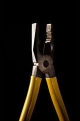 pliers with yellow handles on a black background