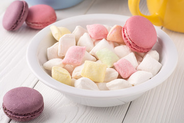 colorful candy and macaroons in a plate and on a table