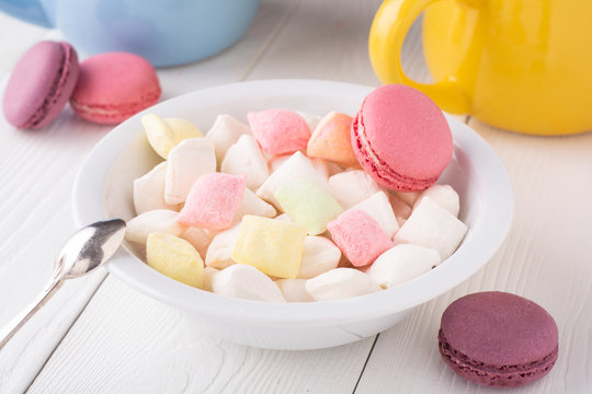 multi-colored sweets and macaroons in a plate.Coffee with colorful candies and macaroons