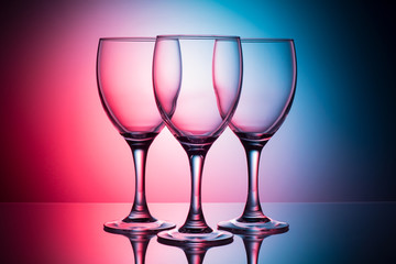 three empty glasses on a blue-pink background
